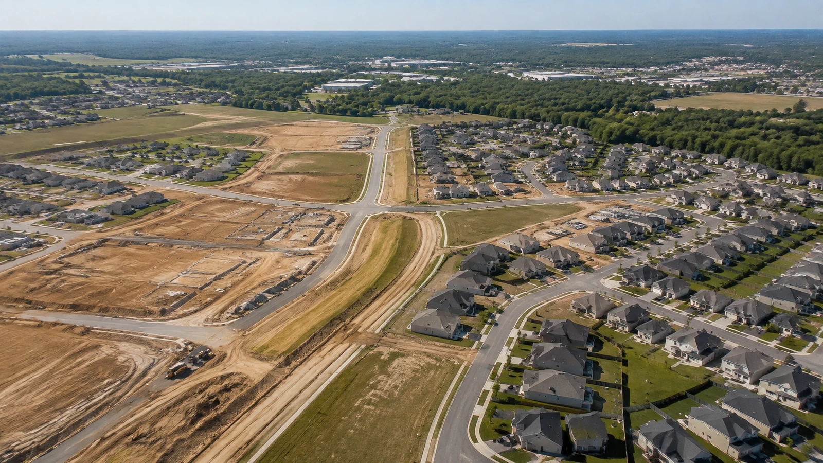Oblique aerial view of completed homes, new streets, and graded construction areas in an expanding suburban neighborhood