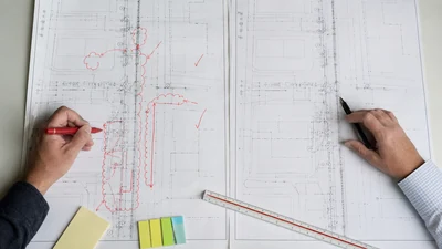 Marked construction plan beside a clean final as-built drawing during document review