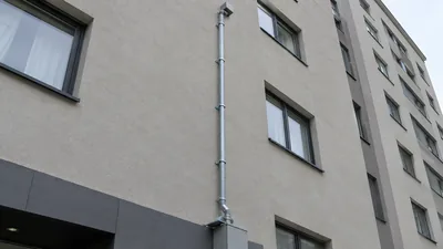 A secured vertical telecommunications conduit riser attached to the exterior wall of a multi-story building.